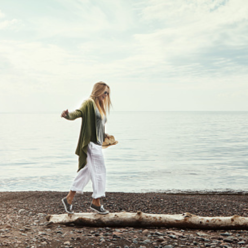 woman on beach walking on large stick